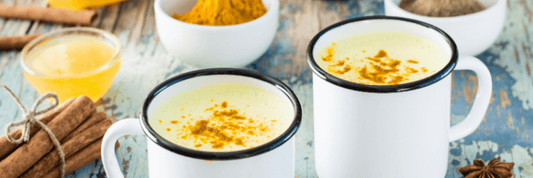 Two cups of black seed oil golden milk in white mugs