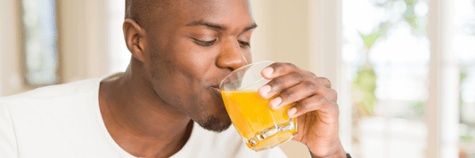 Man drinking soursop living bitters with orange juice out of clear glass