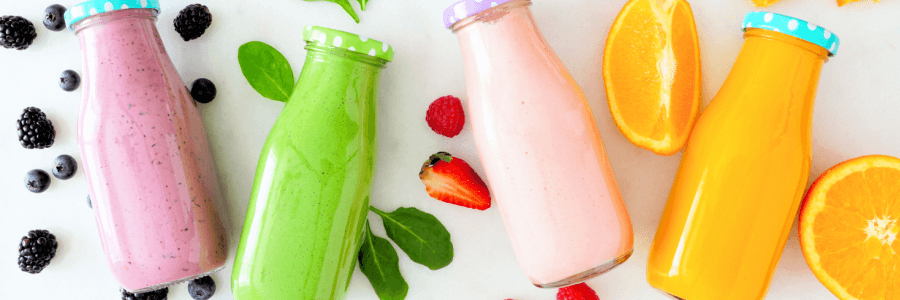 4 jars of fruit infused sea moss gel, purple, green, pink, and orange with fruit lying next to the jars