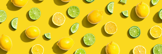 Whole and sliced lemons and limes on yellow background