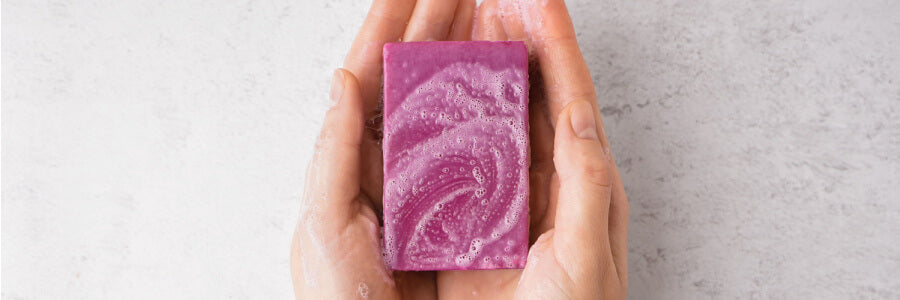 rectangular purple bar of suddsy soap in hands