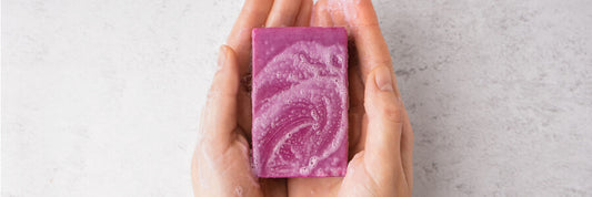 rectangular purple bar of suddsy soap in hands