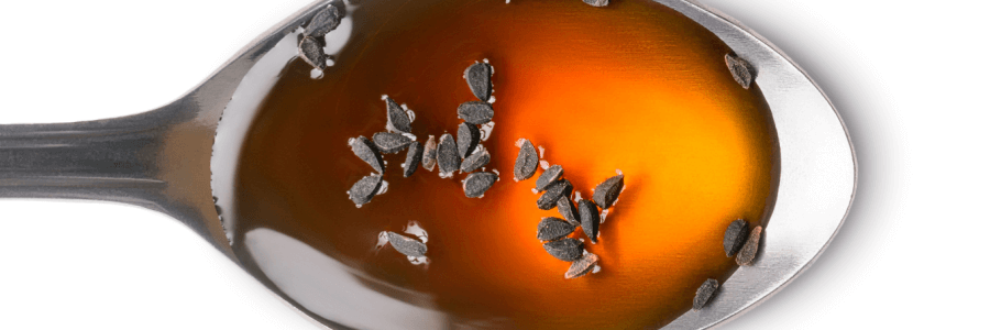 Metal spoon filled with honey and black cumin seeds