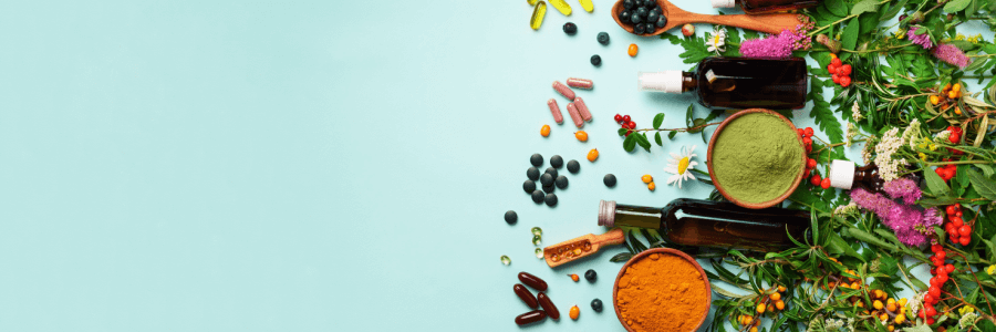 Health supplements in capsule, powder, and raw form lying across light blue background