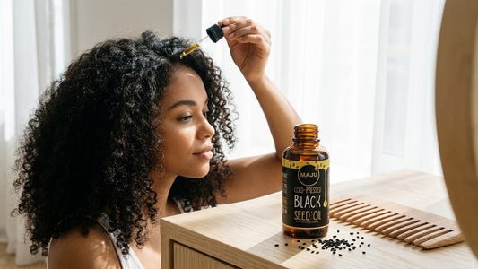 Woman applying MAJU black seed oil to her scalp with a dropper