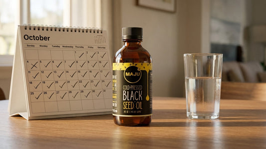 MAJU black seed oil bottle beside a calendar with days checked off
