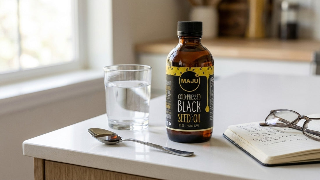 MAJU black seed oil bottle with water glass and research notebook