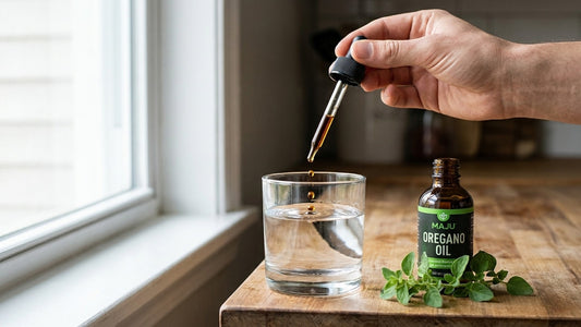 Dispensing drops of MAJU oregano oil into a glass of water
