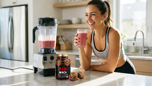 Woman with a smoothie beside MAJU red maca capsules in a bright kitchen
