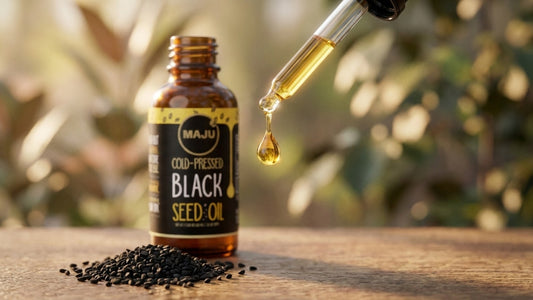 Golden drop of black seed oil falling from a dropper with black seeds below